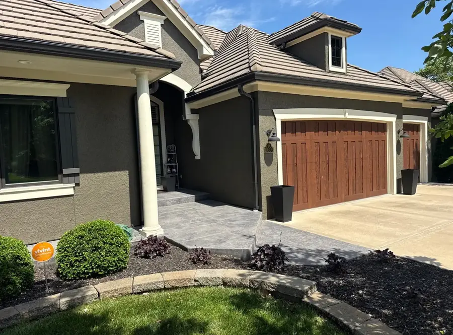 Repainted stucco home exterior with stained wood-look garage doors and crisp white trim