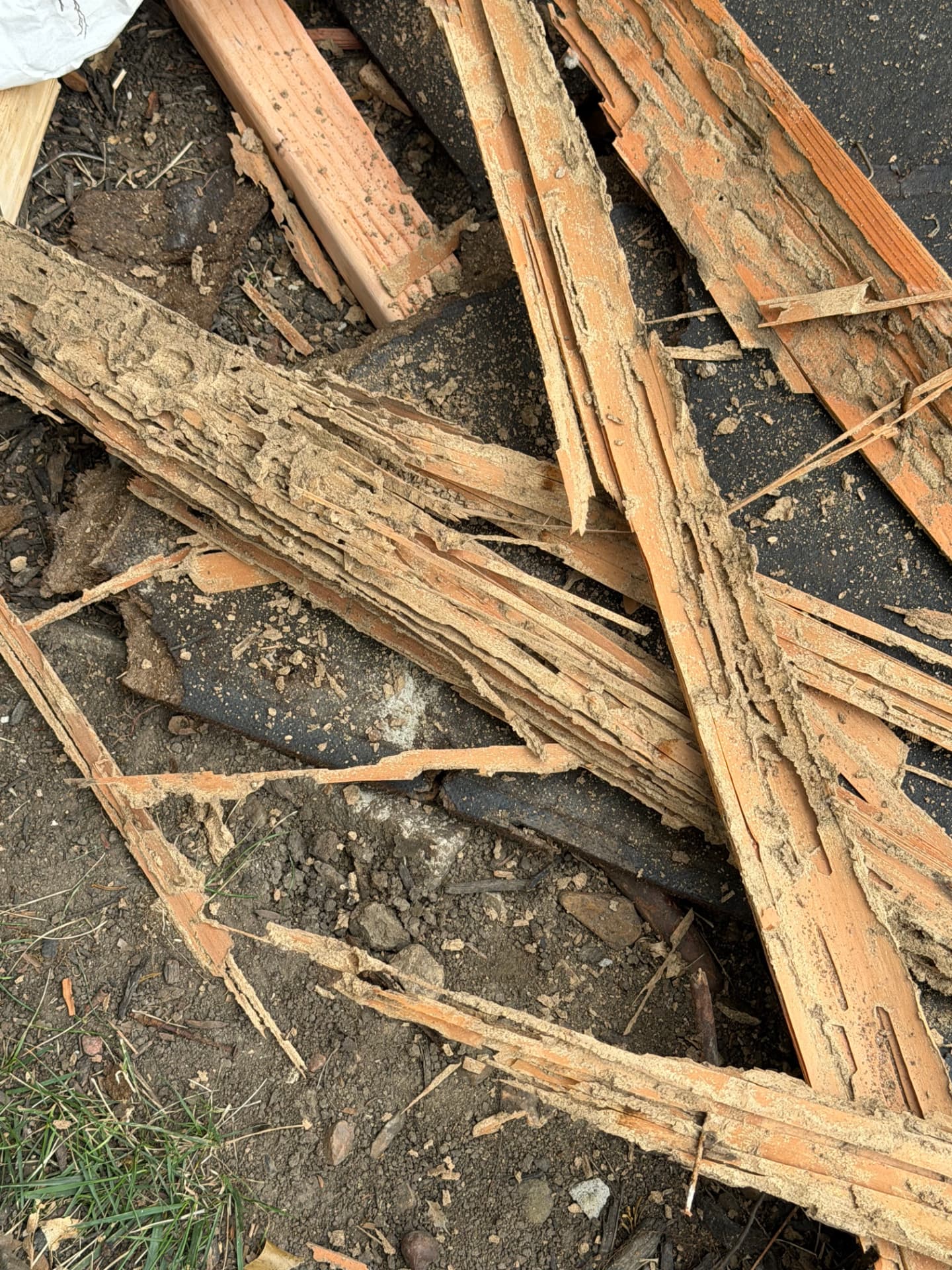 Removed rotted trim boards stacked outside after being cut back to solid material