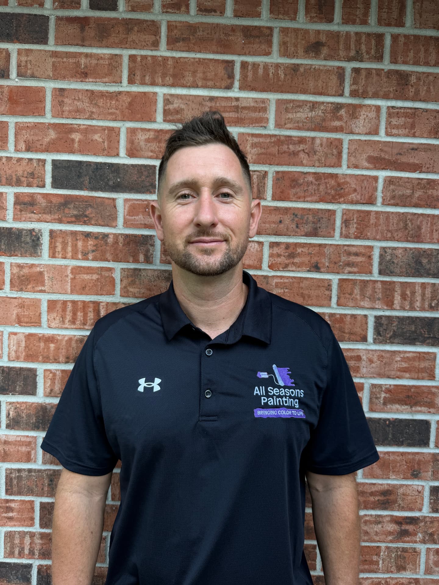 James Griffin, owner of All Seasons Painting, standing in front of a brick wall