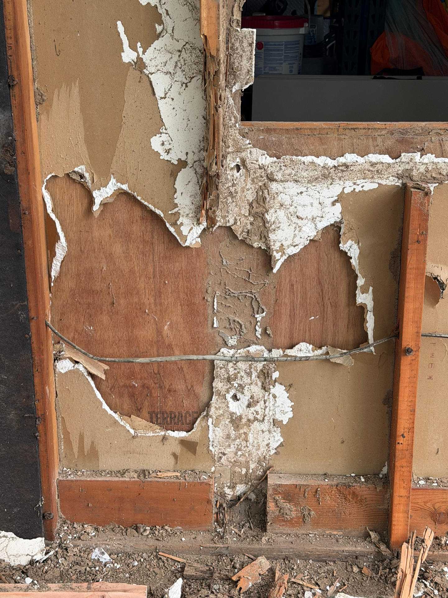 Damaged wood siding and sheathing with peeling paint showing wood rot repair work needed