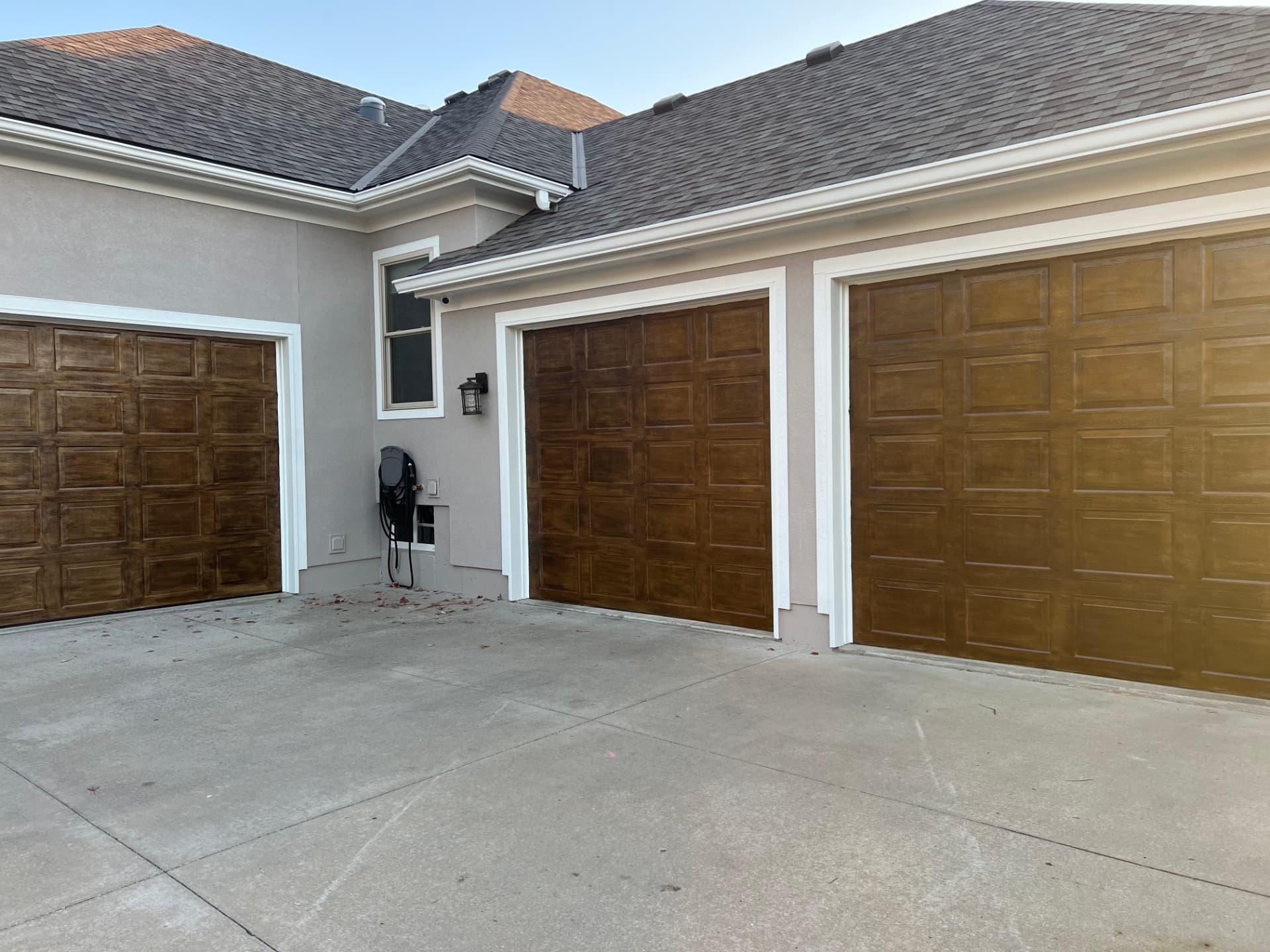 Triple garage with wood-look stained doors and freshly painted gray stucco