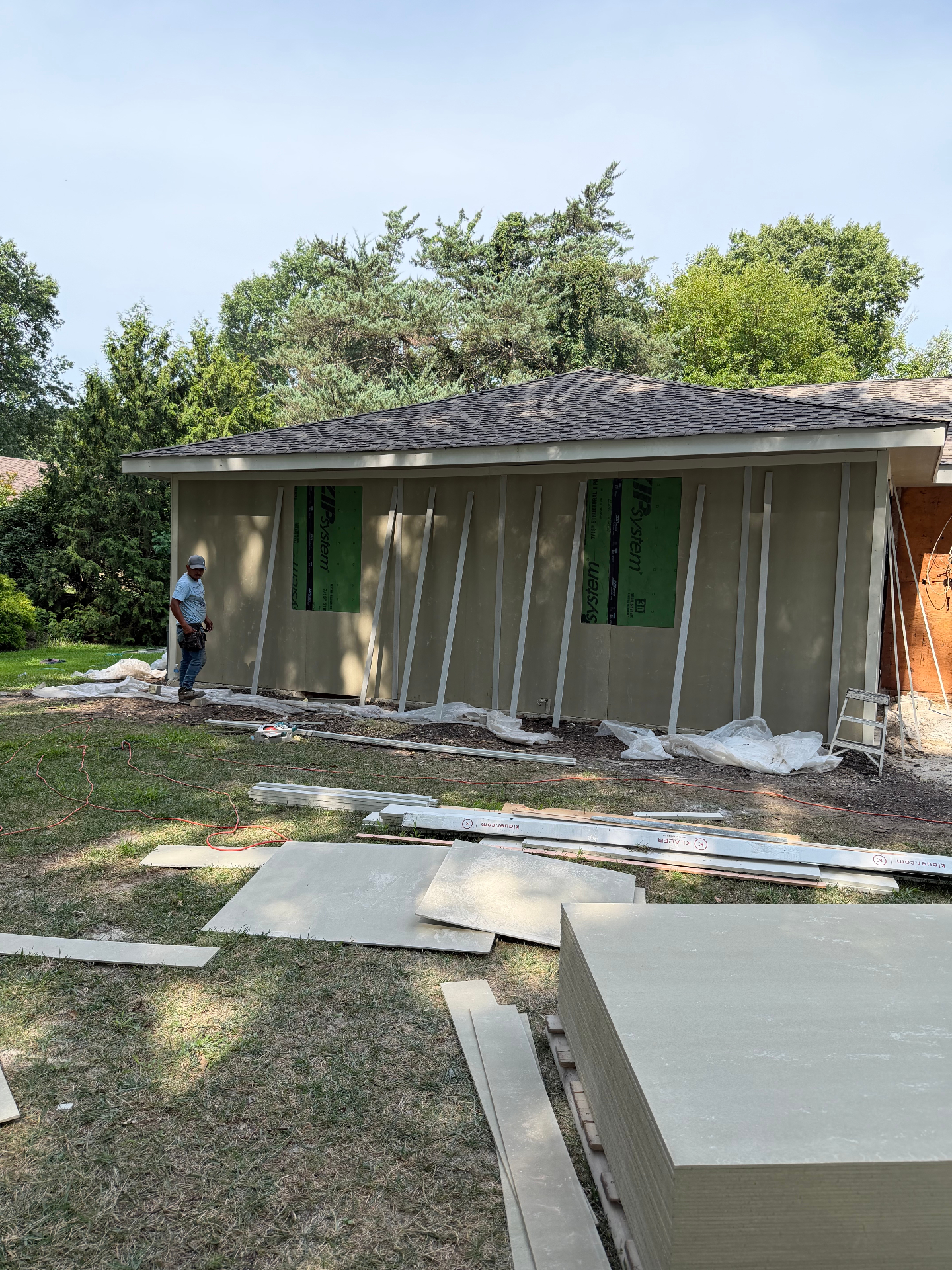 Siding installation in progress on a Kansas City home with sheathing exposed and new trim boards staged